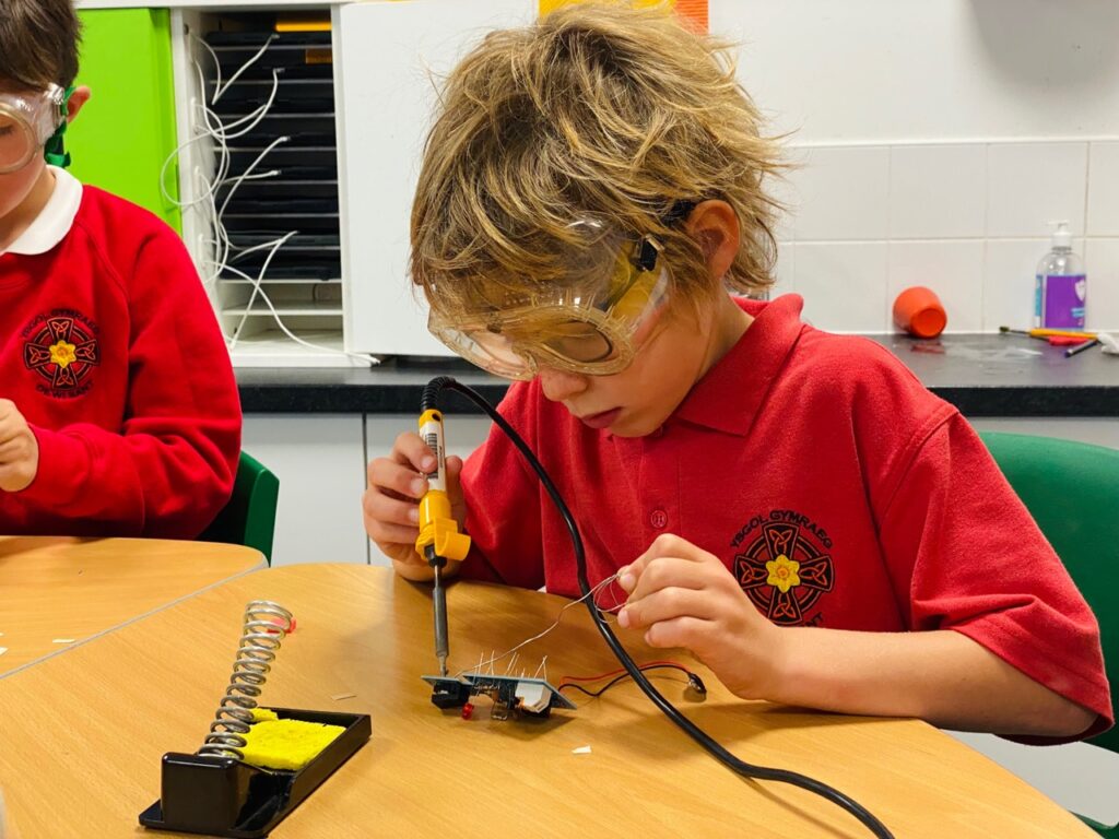 Pupil soldering circuit boards at a desk