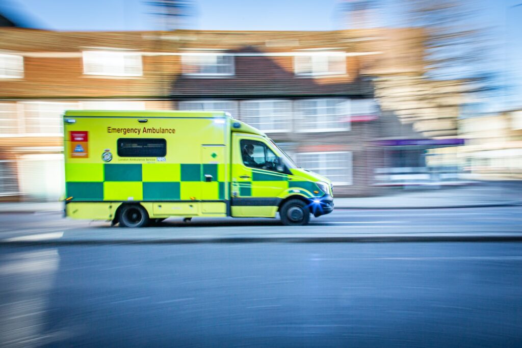 Ambulance moving at speed on a road during daytime