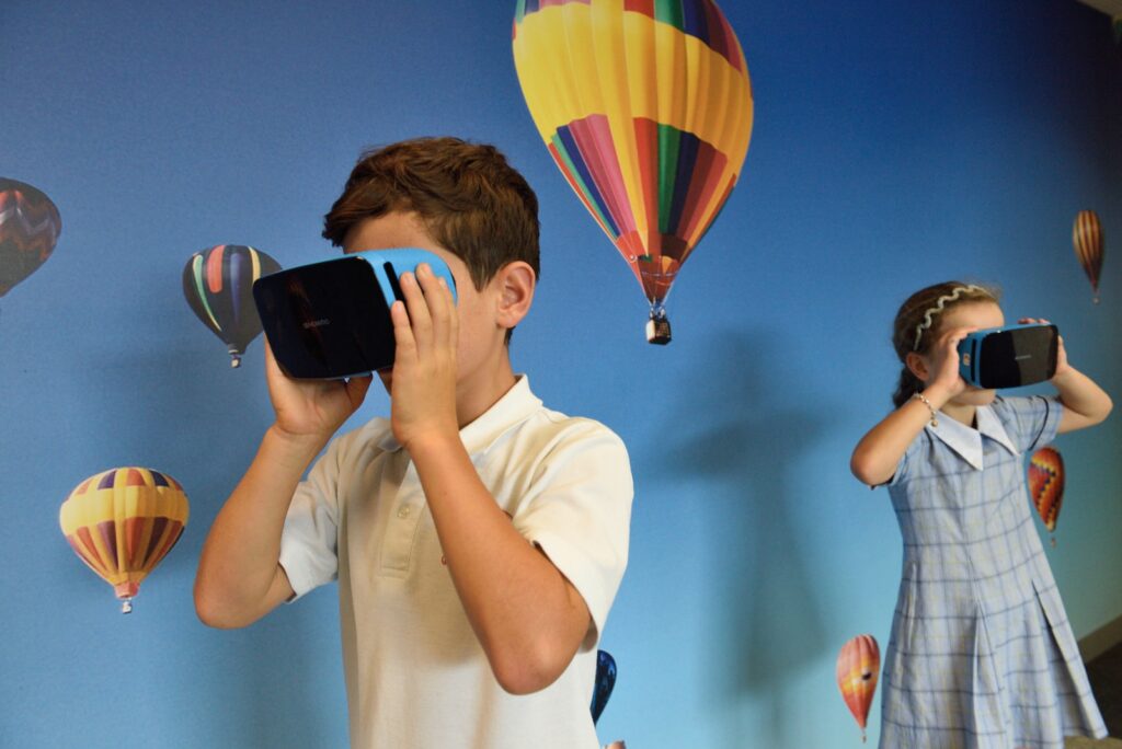 boy and girl uses VR goggles in front of hot air balloons wallpaper