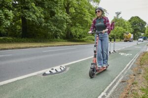 Woman in sunglasses on a Voi e-scooter, photo courtesy of Voi