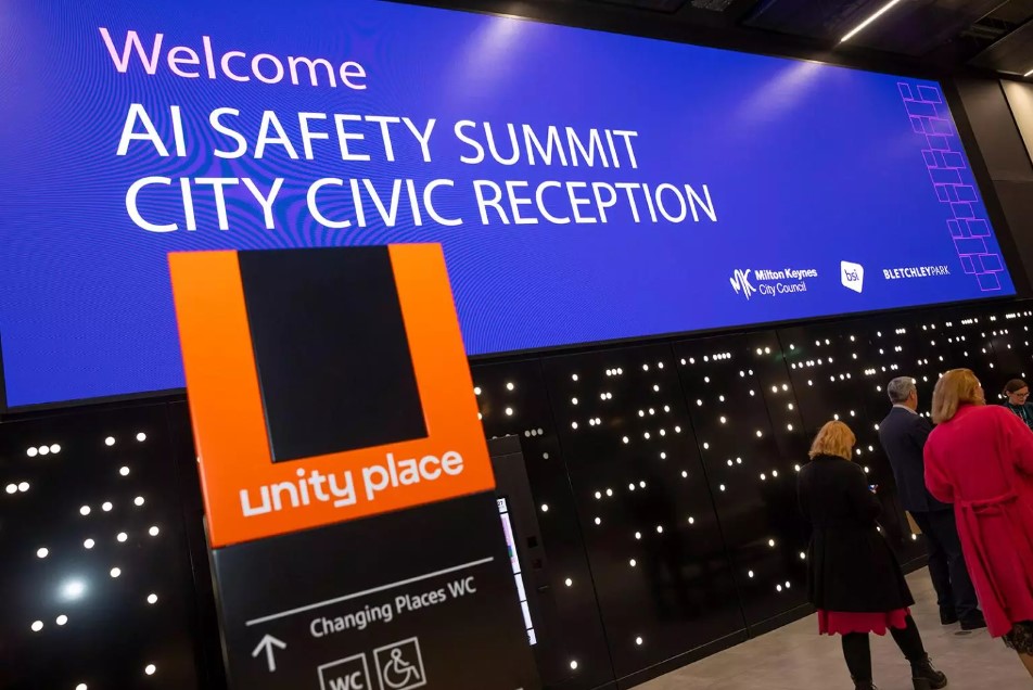 Screen showing sign: 'Welcome [to the] AI Safety Summit City Civic Reception' at Unity Place in Milton Keynes, 2023