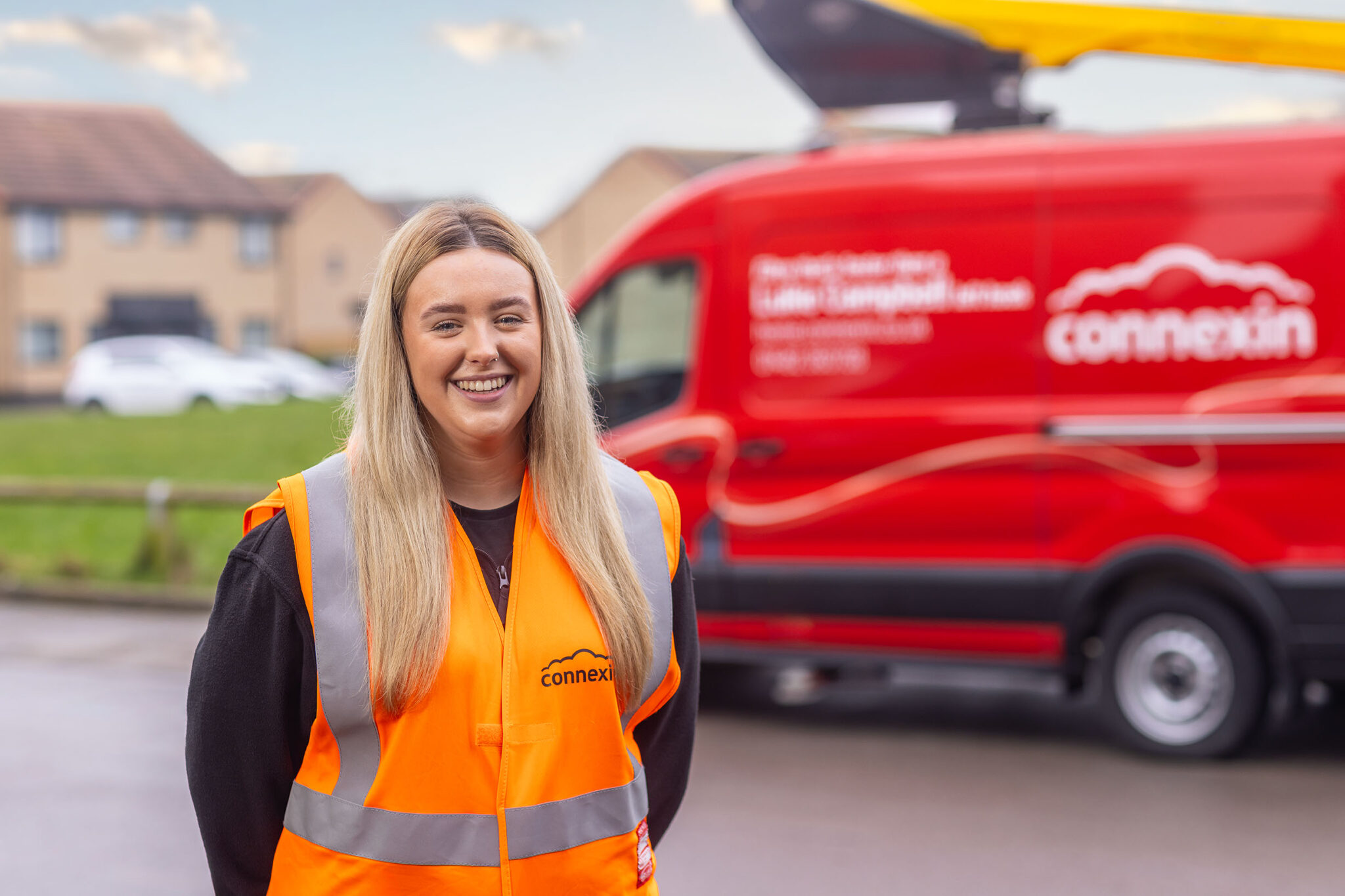 Blond woman in Connexin uniform in front of a red Connexin van