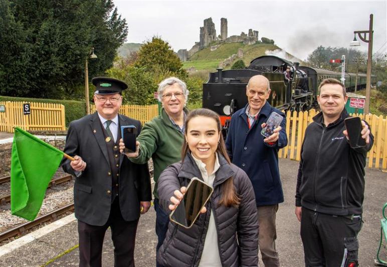 Staff and enthusiasts supporting the new WiFi project at Swanage Railway, with Corfe Castle visible behind them.