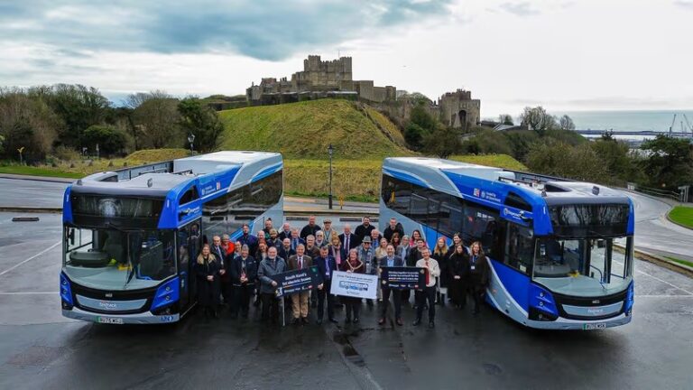 Staff with two of the new blue electric buses running on the Dover Fastrack service, with Dover Castle in the background. Image courtesy of Kent County Council